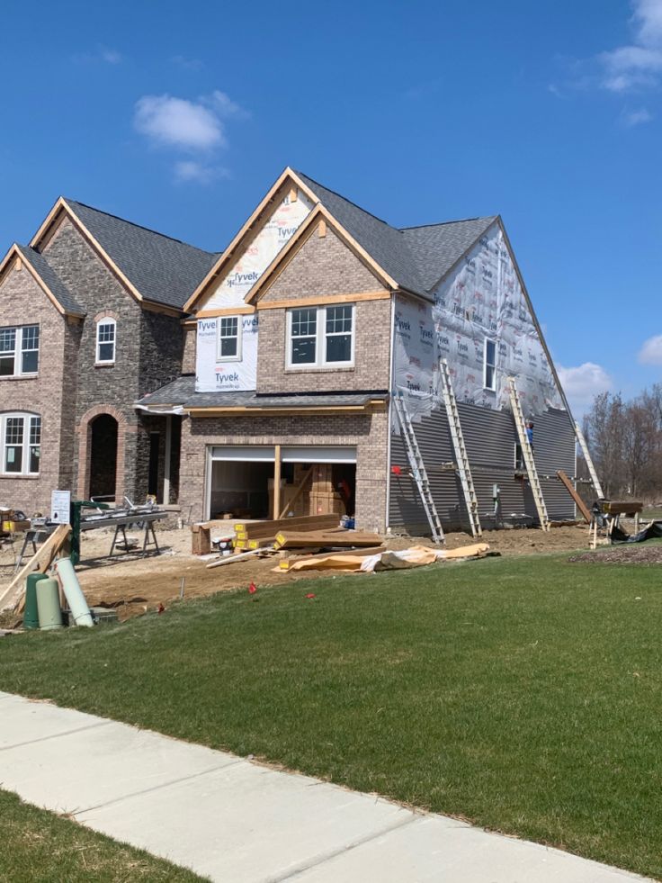 Two-story brick home mid-construction with siding underway